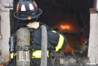 Firefighter with a hoseline over his shoulder confronting the flames