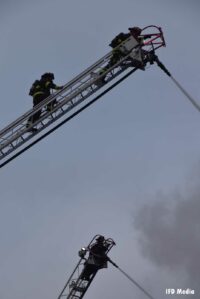 Firefighters on aerial ladders at the fire