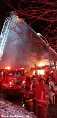 A view of aerial apparatus and firefighters at the house fire