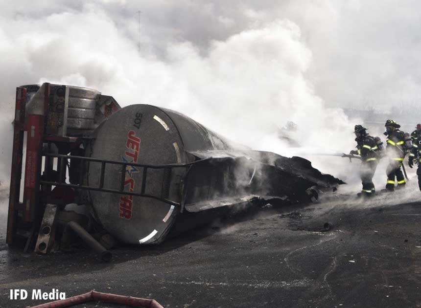 Firefighters train a hoseline on the burning tanker