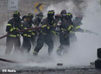 Numerous firefighters advancing a line