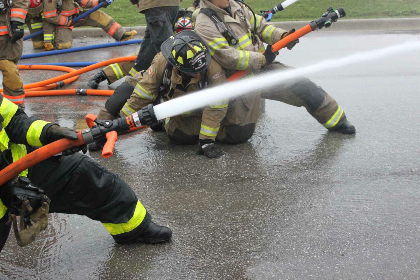 A firefighter on the nozzle extends his leg to check the floor surface in front of him.