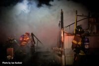 Firefighters work among the ruins of burned mobile home in Dearborn Heights