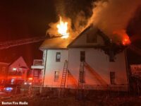 Fierfighters in an aerial as fire vents from a roof