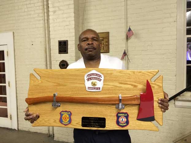 Battalion Chief Frank Ferguson holding his fire ax plaque that was presented by his shift on his last working day.