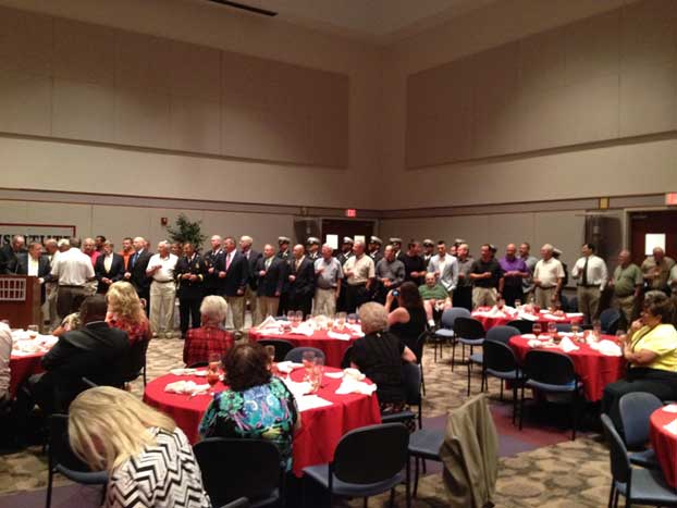 Active and retired firefighters gather at the front of the room to pose a toast for the new retirees.