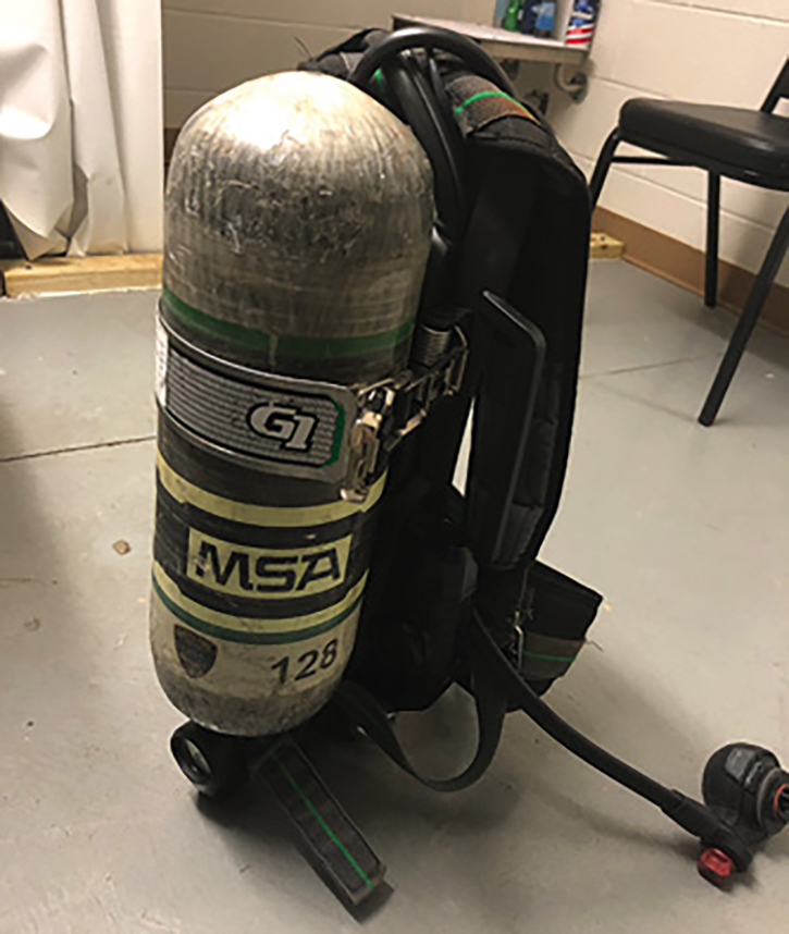 A “blown out” SCBA with straps tangled, bottle disconnected, and bypass open.