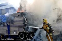 Firefighter applies water to burning trailer