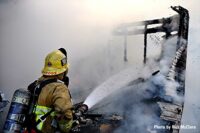 Firefighter turns a hoseline on a trailer fire