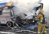 Firefighter sprays water on a burning trailer