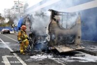 Firefighter navigating around wreckage of burnt trailer