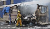 A firefighter trains a hoseline on the burn remains of the trailer