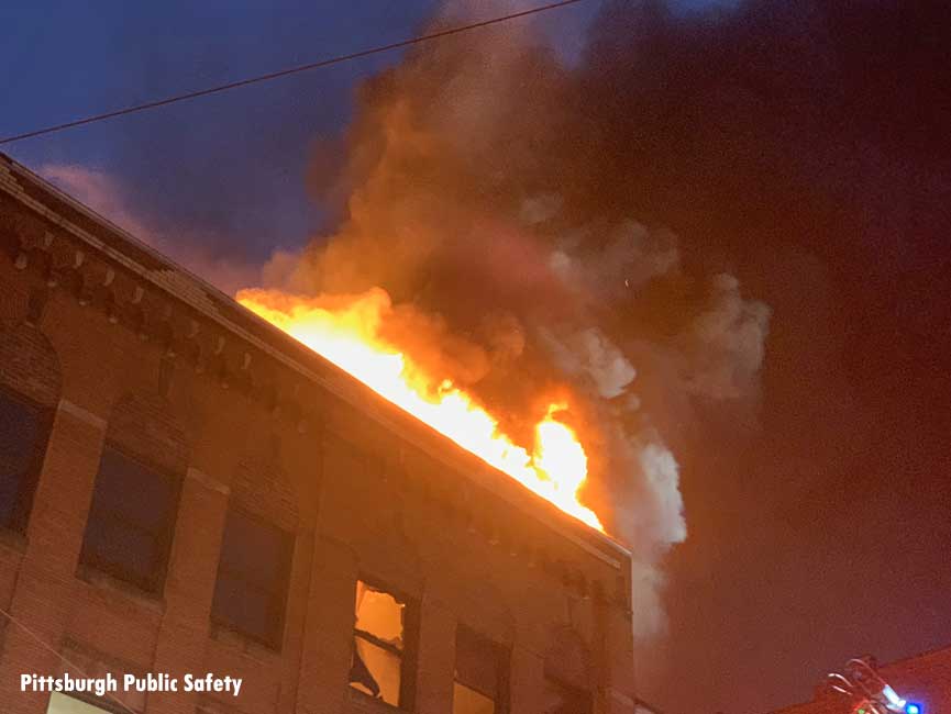 Flames from the fire, which went to four alarms, go through the roof of the building