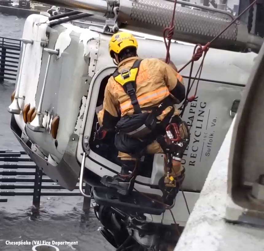 A firefighter is lowered to remove the driver from the cab