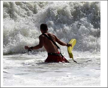 Lifeguard entering the surf with a rescue tube