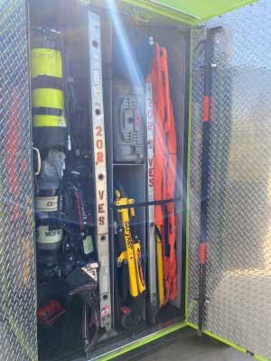 Various firefighter tools including a ladder stored inside a fire truck compartment