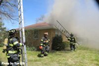 Firefighters begin to raise ladders at the home