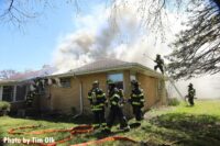 Firefighters begin to make the roof of the fire building