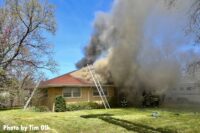 A ladder up to the roof of the vacant home with smoke showing