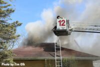 Firefighters in tower ladder bucket over house fire