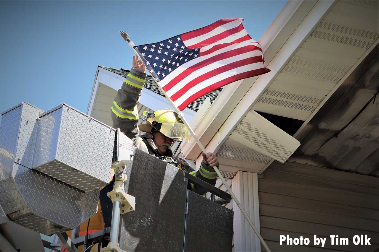 A firefighter retrieves an American flag from the scene of a major apartment fire in East Troy