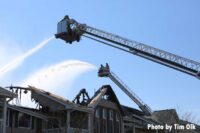 Tower ladder buckets with elevated master streams pour water on the fire