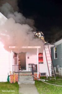 A firefighter climbs a ladder and makes it on to the roof amidst smoke