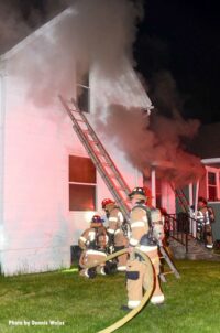 Smoke on scene as firefighters throw a ladder at the house fire