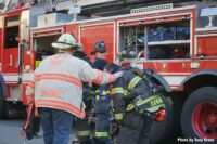 A firefighter hunched over on the fireground surrounded by other firemen