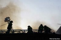 Firefighters on an aerial device with smoke in the background