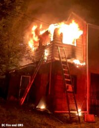 View of a ladder and massive flames venting from a building in D.C.