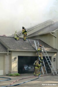 Firefighters stretch a line onto the roof of the building