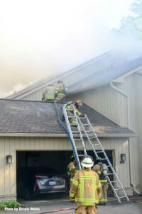 Firefighters raise two ladders at the scene of a fire in Bloomfield, Michigan