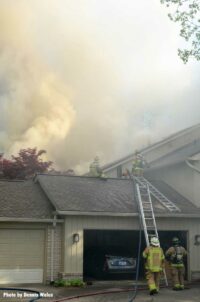 Firefighters on the roof with smoke billowing out of the condo