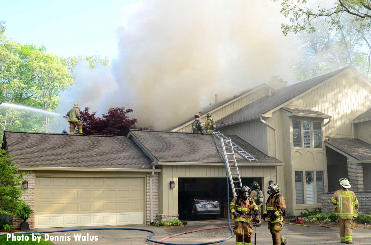 Firefighters with ladders at the scene of the condo fire in Michigan