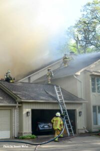 Firefighters operate on the roof of the building during a condo fire