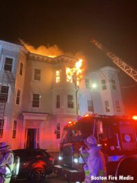 An elevated stream as fire shoots from the top of a building in South Boston