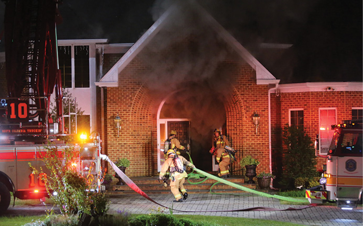 Firefighters pulling lines at fire scene