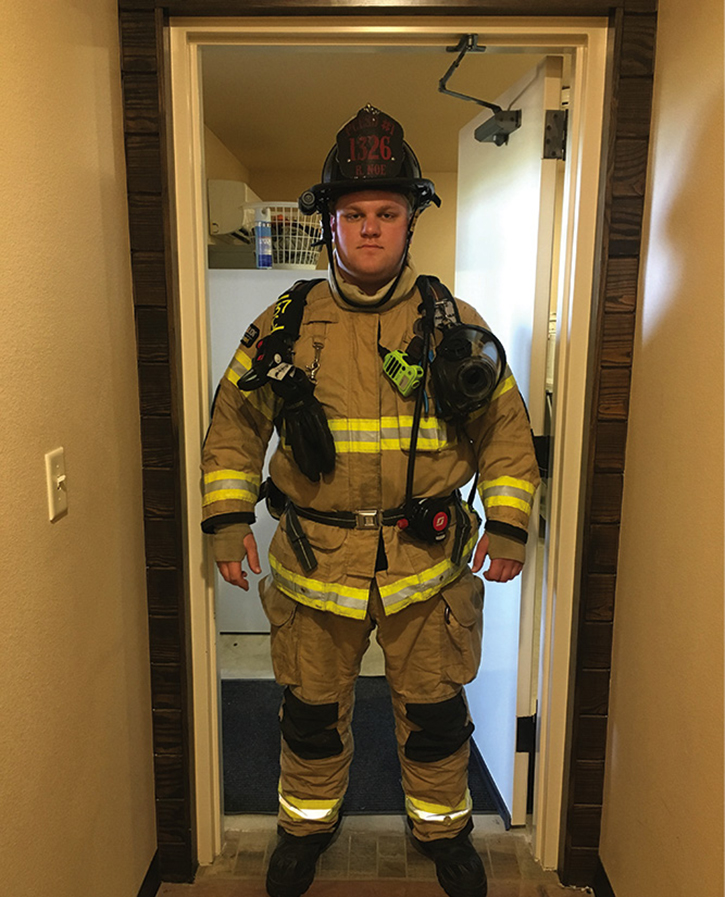 A firefighter stands in a doorway in gear. Note the clearance issue at his shoulders because of the gear.