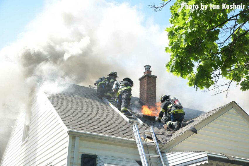 Firefighters perform vertical ventilation on the roof of a house fire