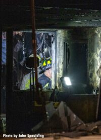 Firefighter surveys fire damage inside a building