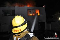 Los Angeles firefighter with hose stream through window on flames