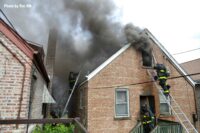 Dark smoke emerges from windows and roof of home