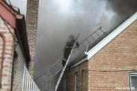 Firefighter brings ladders up to the roof