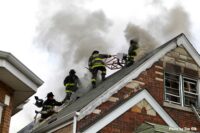 Multiple Chicago firefighters working on the roof of a home