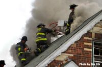 Firefighter with a power saw operating on the roof of a home