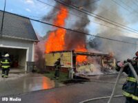 Flames shoot from a structure in Indianapolis as firefighters work