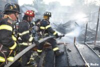 Firefighters with a hoseline blasting water on a fire