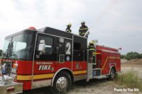 Firefighters on top of fire truck with master stream