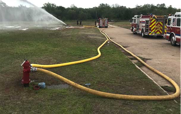 Two lines running into a fire hydrant with fire trucks